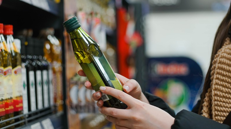 person holding bottle of olive oil