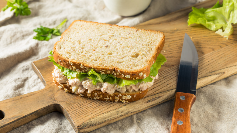 Tuna salad sandwich on cutting board with knife