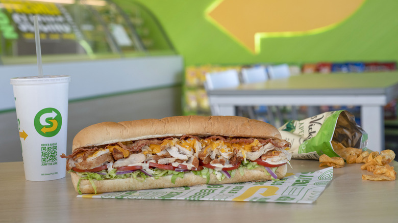 Subway sandwich, chips, and drink on restaurant table.