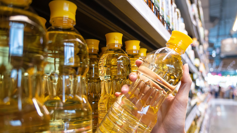 Hand picking bottle of cooking oil from shelf