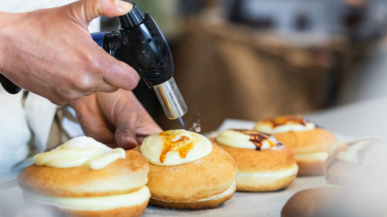 Baker caramelizing topping on donut