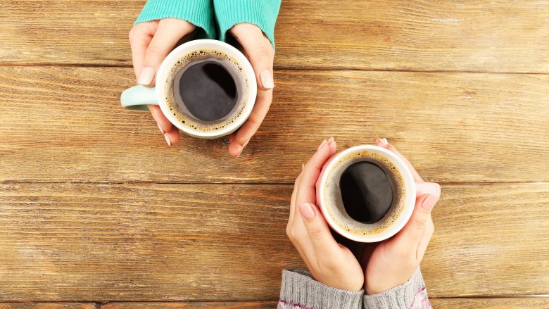 Two sets of hands holding cups of coffee