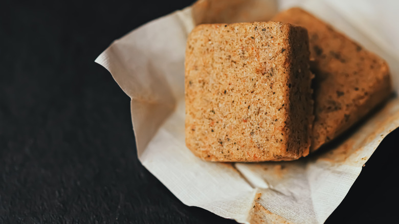 Two unwrapped vegetable bouillon cubes sitting on a wrapper