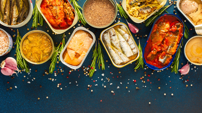 tinned fish on a dark background surrounded by herbs and spices