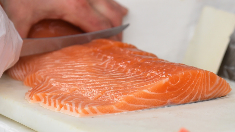 chef portioning raw salmon fillets