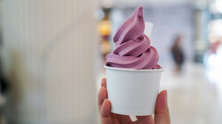 Hand holding purple frozen yogurt in a cup
