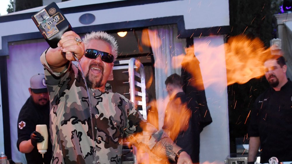 Guy Fieri cooking over fire.