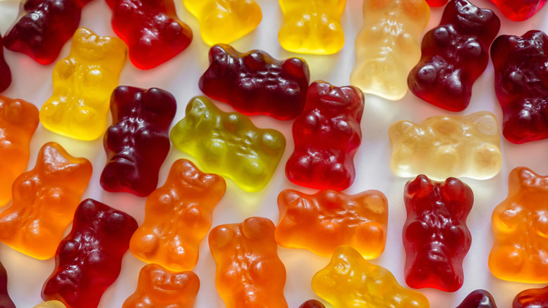 A bunch of multi-colored gummy bears lie on a table.