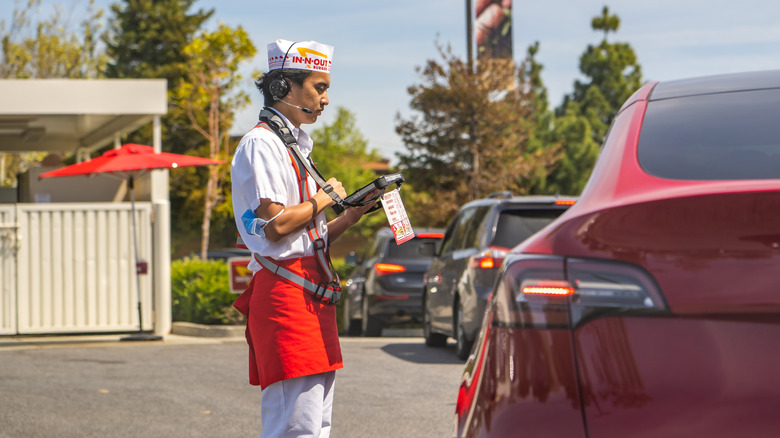 In-N-Out worker taking order from customer in red car at drive-thru