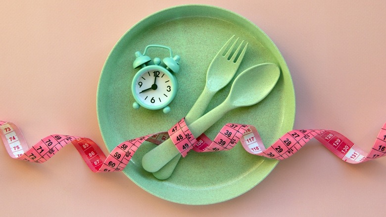 green plate with clock and tape measure for intermittent fasting