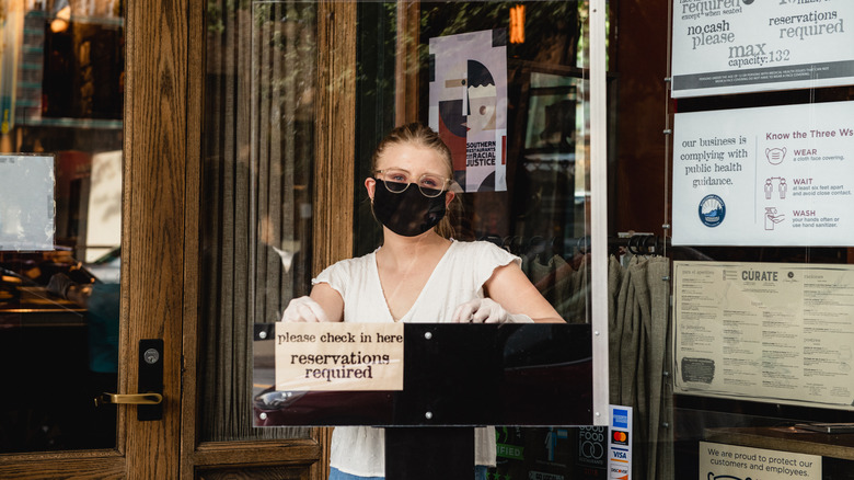 Restaurant host in mask at podium