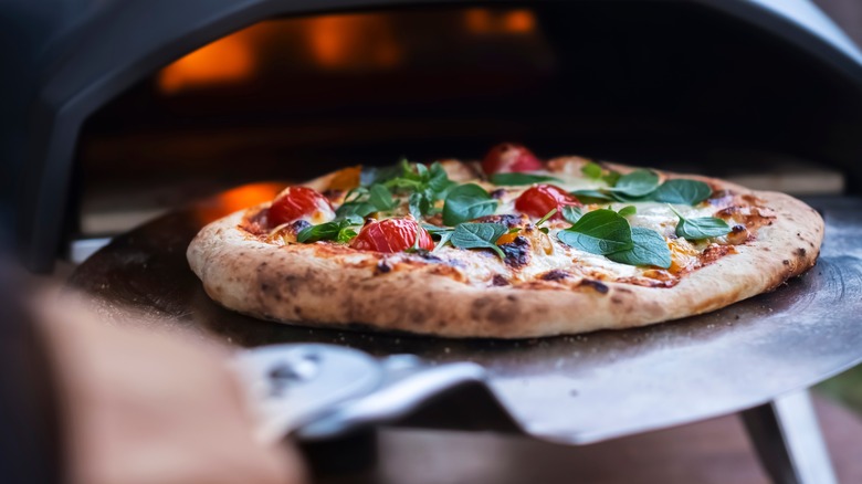 Pulling pizza from the oven