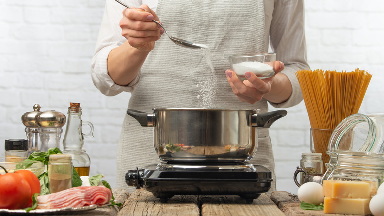 cook adding salt to pot