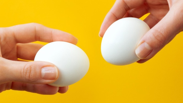 Two hands holding eggs facing each other