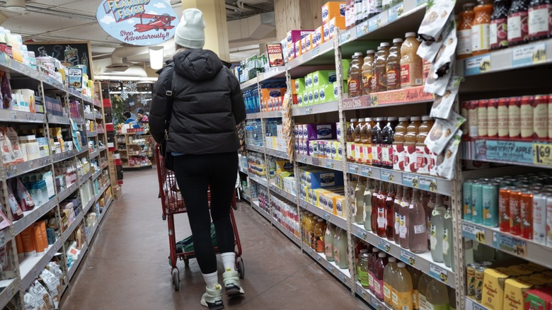 Person dressed in winter clothes pushing a shopping cart down a Trader Joe's aisle
