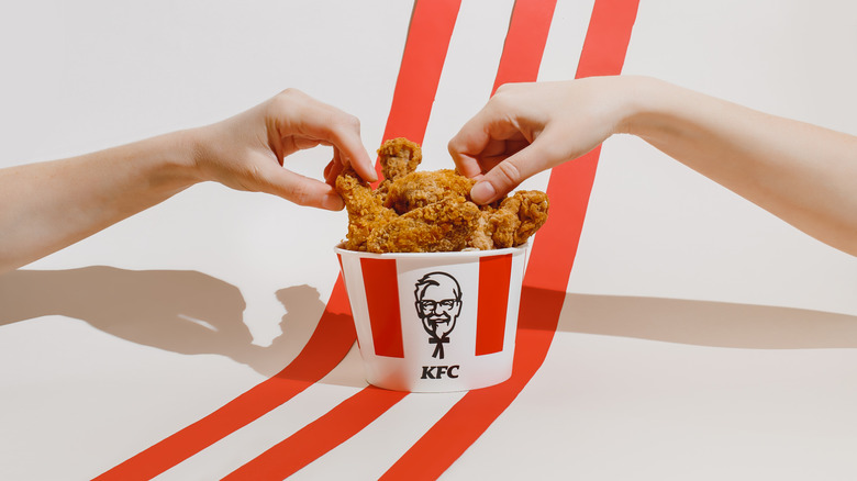 two hands reaching for KFC bucket