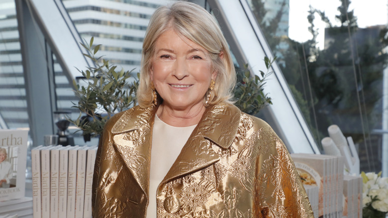 Martha Stewart in a gold embossed jacket standing in front of her books