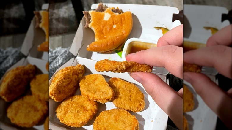 A diner holds up a Chicken McNugget to show how thin it is.