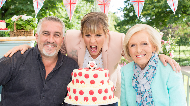 Paul Hollywood, Mel Giedroyc, and Mary Berry with a cake. 