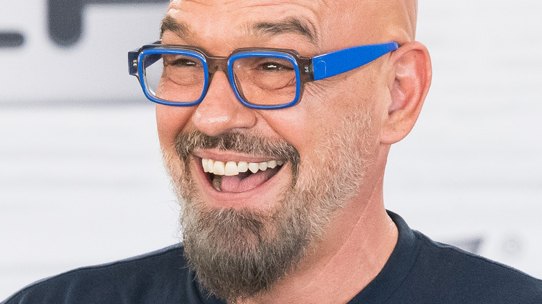 Michael Symon smiling widely in blue glasses
