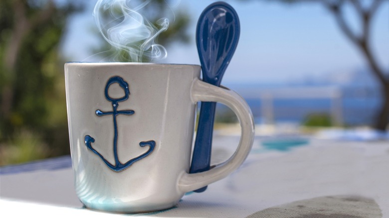 A ceramic coffee mug with an anchor on it.
