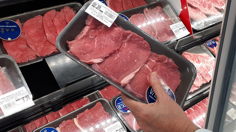 Shopper holding meat in grocery store