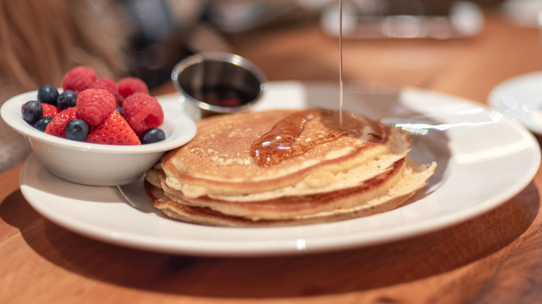 Syrup pouring over pancakes on plate