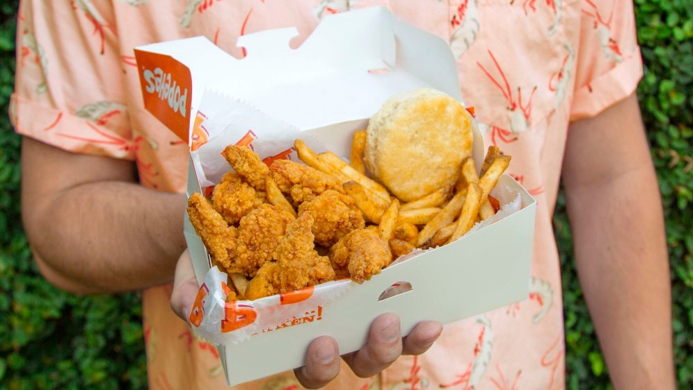 Person holding box of Popeyes fried shrimp, fries, and biscuit