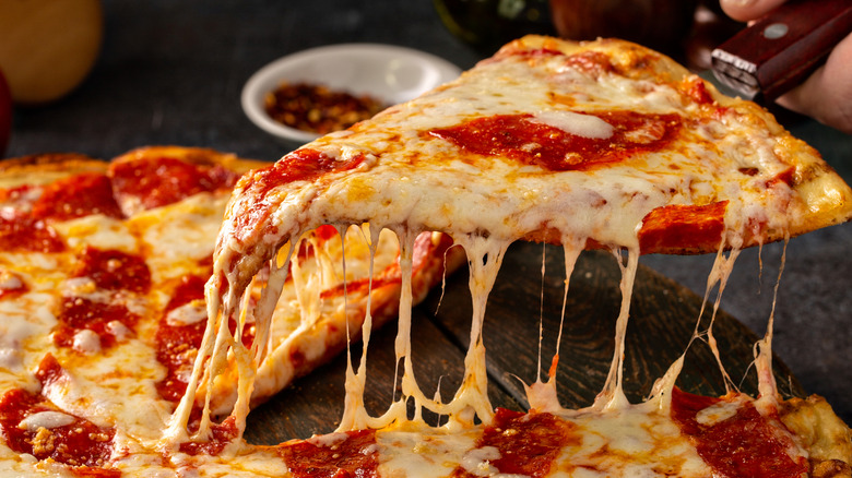 cheesy pizza slice on a wooden platter