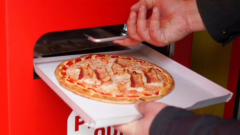 Machine-made pizza on white tray