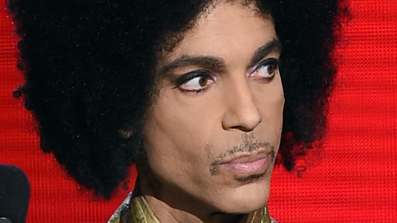 Prince, looking off-camera with a red background