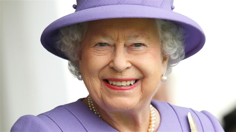Queen Elizabeth II smiling in purple hat