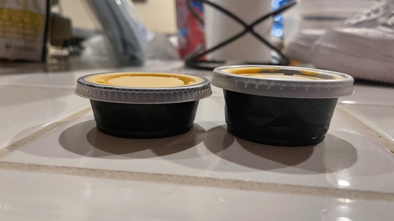 two cups of nacho cheese from taco bell, one is smaller