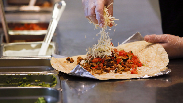 A Chipotle employee making a burrito