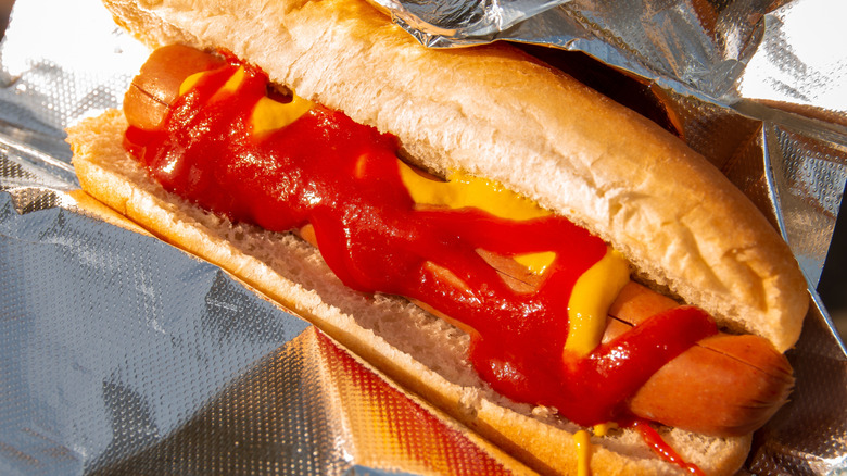 Hot dog with ketchup and mustard wrapped in tin foil