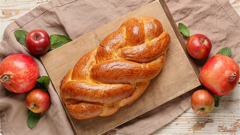 Braided challah surrounded by apples and pomegranates