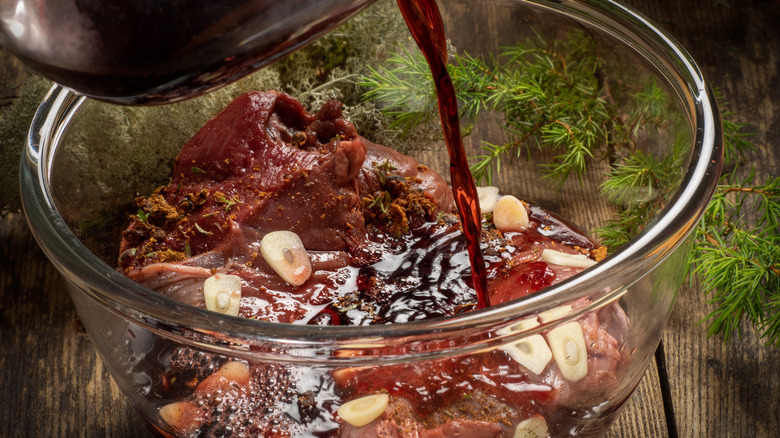 Meat marinating in a bowl of wine, garlic, and herbs
