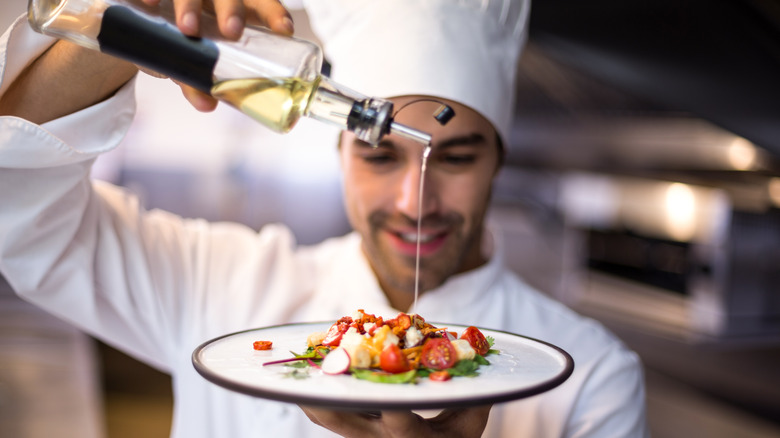 Chef drizzling dish with olive oil