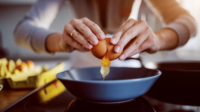 Person breaking egg over bowl