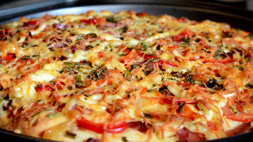 Pizza covered with toppings on a metal plate