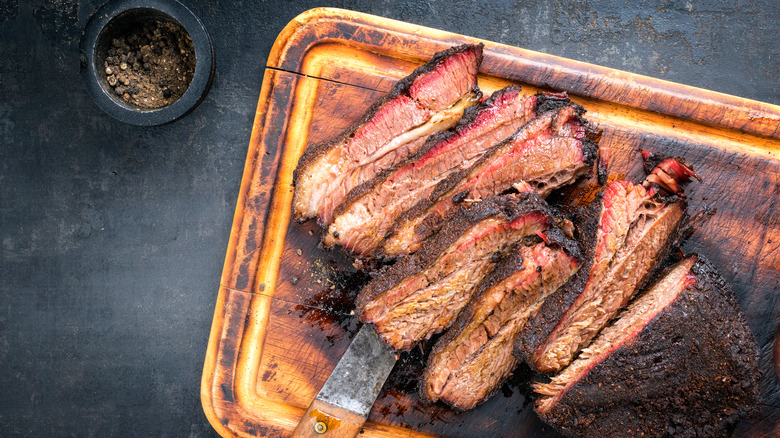 Sliced smoked brisket on cutting board with rub