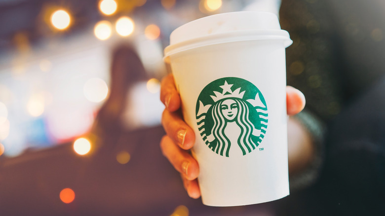 Hand holding white Starbucks cup