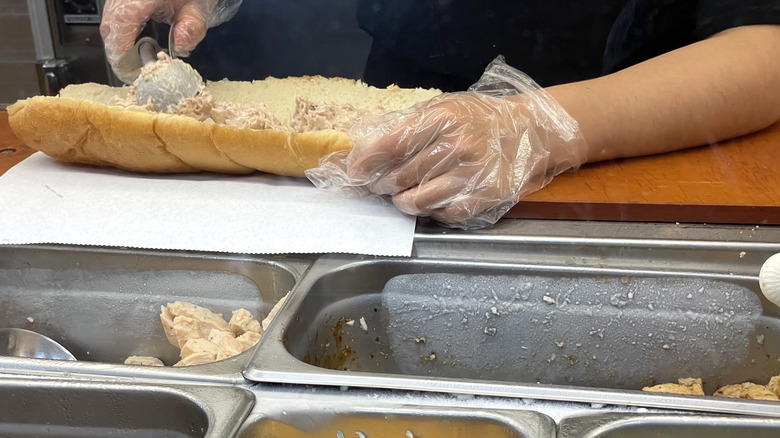person filling subway tuna sandwich