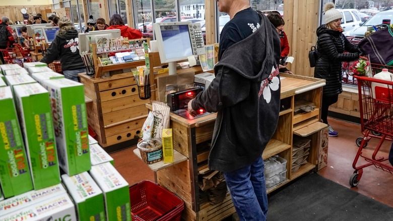 Rows of the Trader Joes checkout aisles with cashier standing behind the nearest podium.