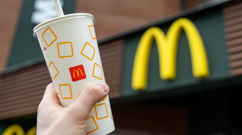 mcdonald's cup with straw in front of mcdonald's logo
