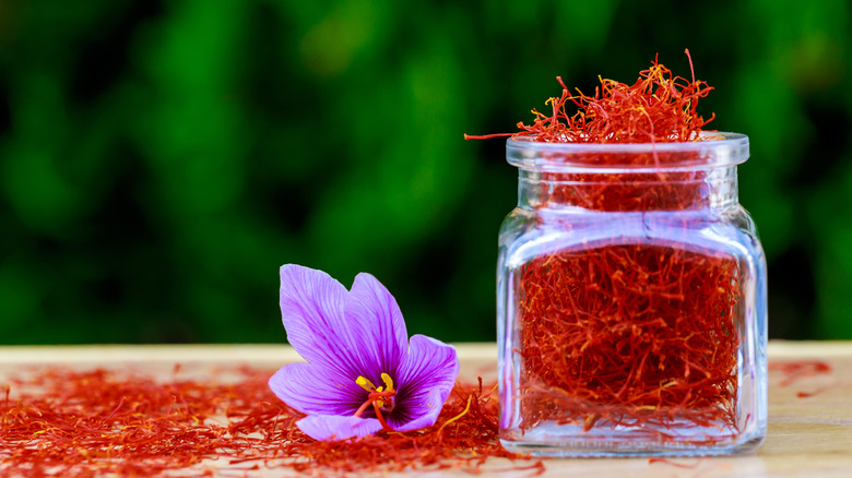 dried saffron in glass bottle next to flower