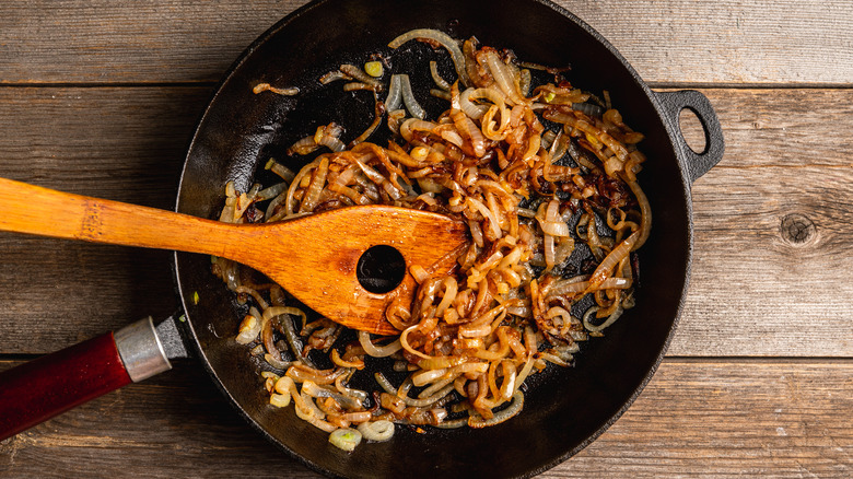 caramelized onions in a frying pan with wooden spoon