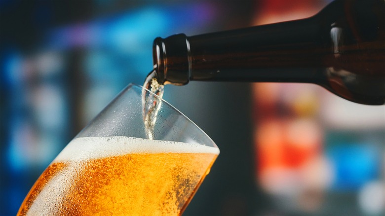 Beer being poured into a glass from an amber bottle.