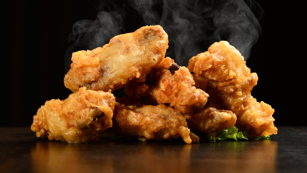 Steaming hot fried chicken on black background