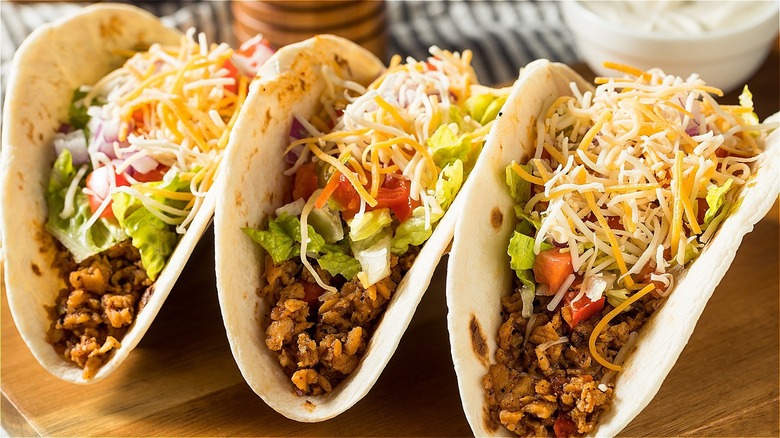 three tacos with meat and cheese